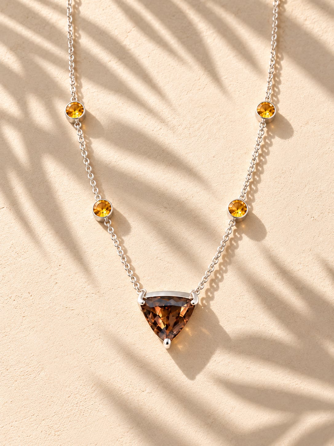 Brown triangular pendant on a silver-coloured chain in warm sunlight